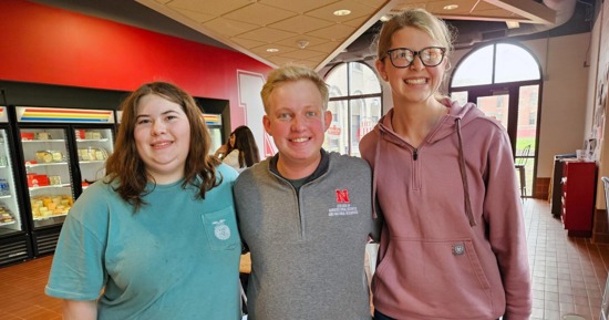 Carie Goodwater (left) and Melany Preister (right), students at Boone Central High School, pose with Brian Mock (center), a Husker student mentor who graduated in May.